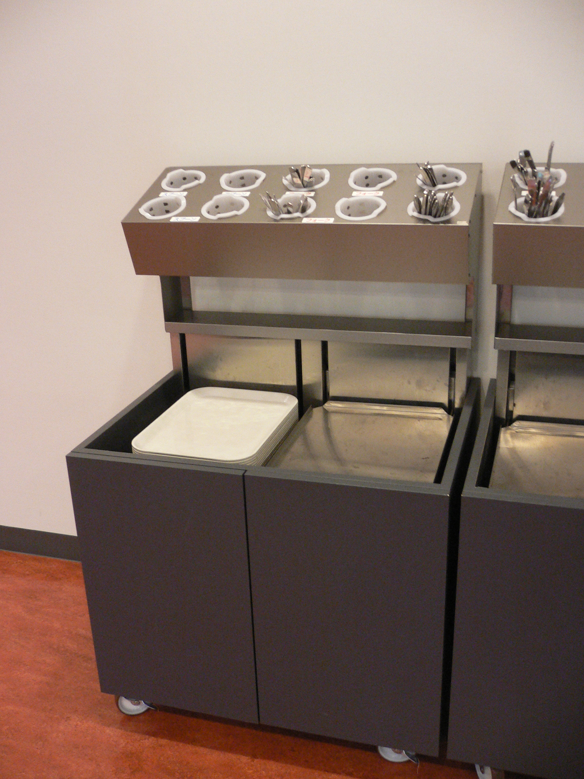 A stack of trays at a cafeteria. Only the topmost tray is visible due to a built-in spring.